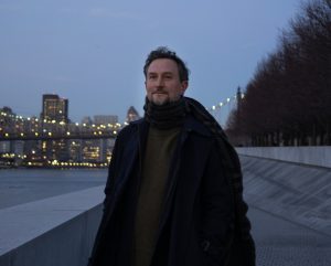 Photograph of Hans Rosenstrom at FDR Four Freedoms Park with the NYC skyline and Queensboro Bridge and the Manhattan skyline in the background